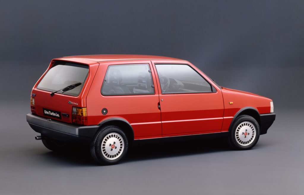 Fiat Uno Turbo vermelho em vista lateral traseira